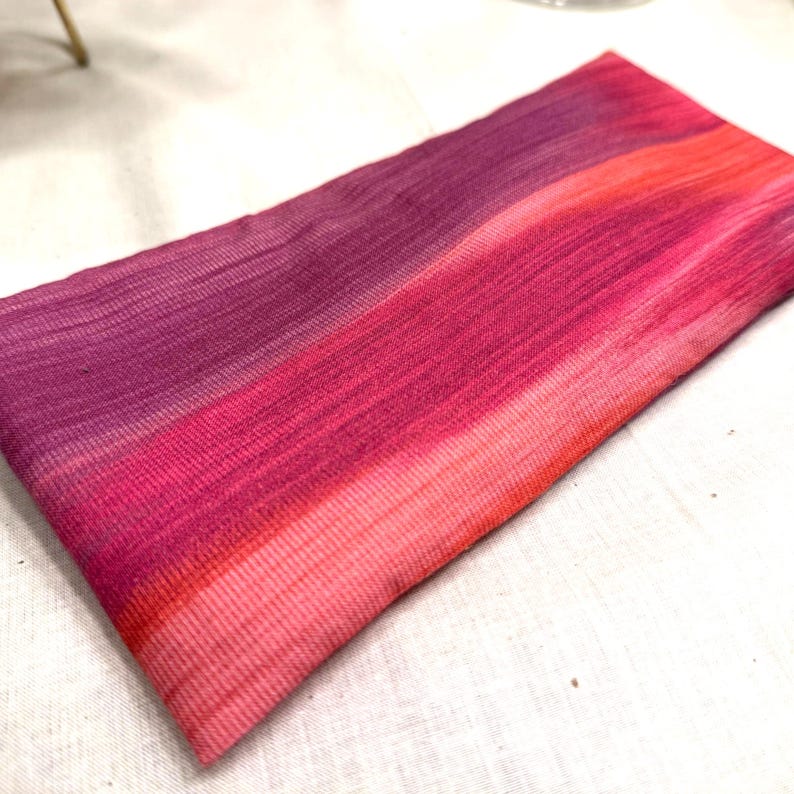 Puede incluir: Un textil rectangular con un degradado de colores, que transita del morado intenso al rosa vibrante y coral. La tela tiene una apariencia texturizada, con l&iacute;neas horizontales visibles. La est&eacute;tica general es suave y colorida.