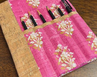 Cuaderno con cubierta de corcho metálico dorado y composición floral rosa, con bolsillos para bolígrafos