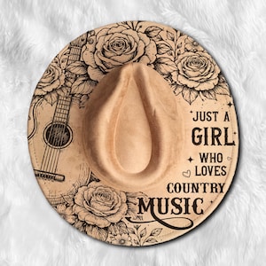 Puede incluir: Sombrero estilo fedora color beige con diseño floral y guitarra. El sombrero presenta el texto negro "JUST A GIRL WHO LOVES COUNTRY MUSIC". Tiene una corona en forma de lágrima y ala ancha.