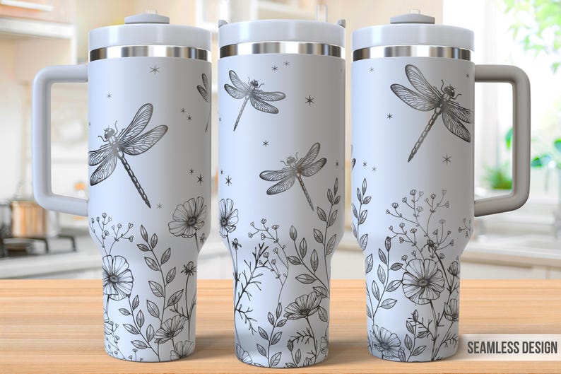 May include: A white stainless steel travel mug with a black and white dragonfly and floral design. The mug has a handle and a lid.