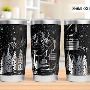 May include: Three stainless steel tumblers with a black background and a silver design of a mountain scene with a ski lift. The design is seamless and wraps around the tumbler.