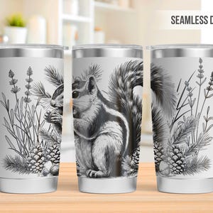 May include: A white stainless steel tumbler with a black and white illustration of a squirrel eating a pine cone. The design is repeated seamlessly around the tumbler. The tumbler is 20 ounces.