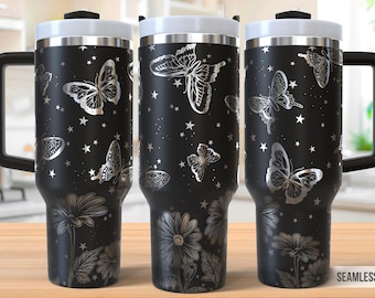 Op de afbeelding: Een zwarte roestvrijstalen reistumbler met een zilveren vlinderontwerp en een zwarte handgreep. De tumbler heeft een deksel met een zilveren ring rond de bovenkant. De tumbler staat op een houten oppervlak.