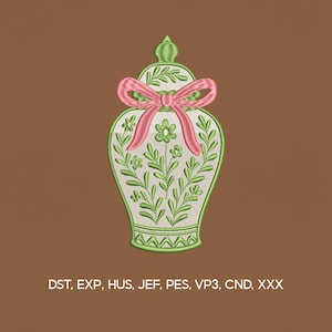 May include: An embroidered design of a decorative vase with a lid, featuring green floral patterns and a pink bow. The vase is outlined in green and filled with a cream color. The background is a solid brown. The image includes the text: DST, EXP, HUS, JEF, PES, VP3, CND, XXX.