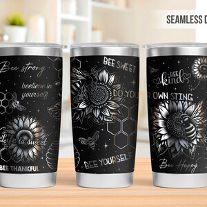 May include: Three stainless steel tumblers with black backgrounds and bee-themed designs. Each tumbler features a sunflower, bees, and inspirational phrases like "Bee Strong" and "Bee Kind". The tumblers have a seamless design.