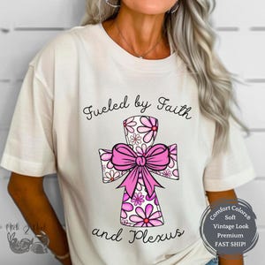 May include: White t-shirt with a pink floral cross and the text "Fueled by Faith and Plexus".