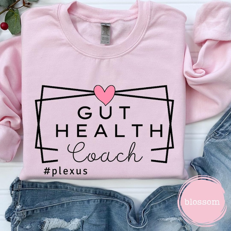 May include: Pink sweatshirt with a black and white graphic that says "Gut Health Coach" with a pink heart above the text and the hashtag "#plexus" below the text.