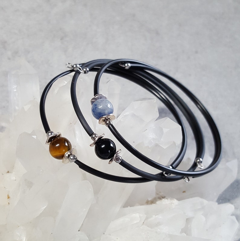 May include: Three black rubber bracelets with silver accents and gemstone beads. The beads are blue, brown, and black.