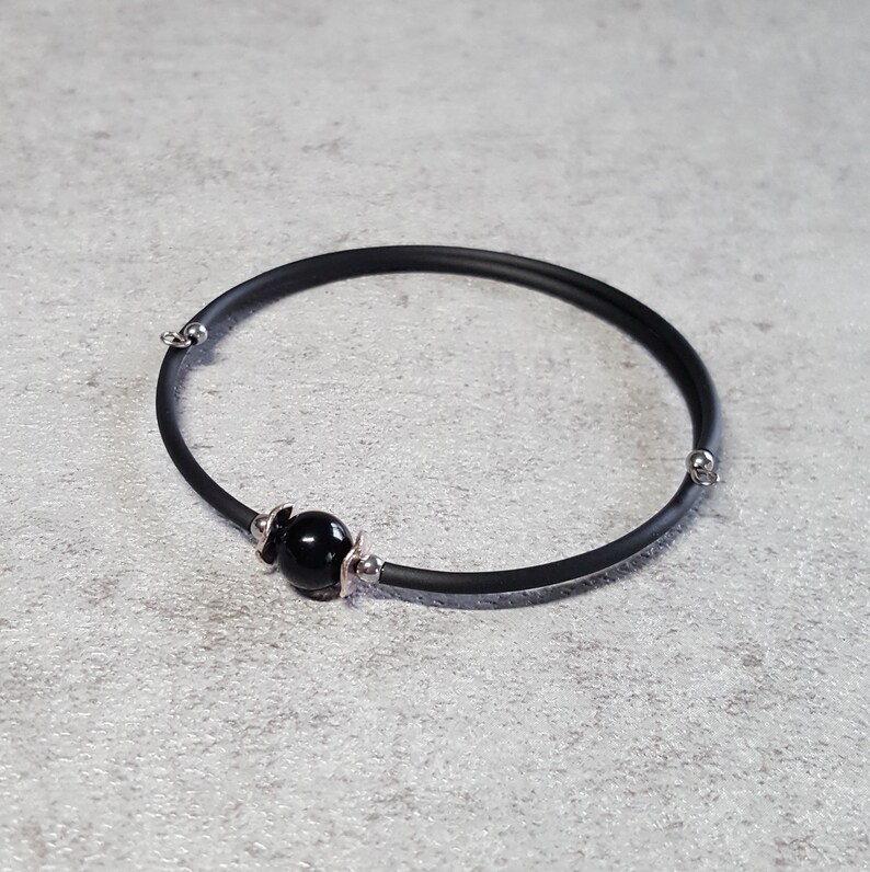 May include: A black rubber bracelet with a single black bead and silver accents.