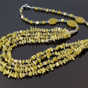 May include: A multi-strand necklace made of light green jade stones. The necklace is layered with multiple strands of small, irregular shaped jade beads. The necklace is accented with silver beads and larger, round jade stones.