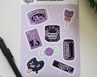 May include: A sticker sheet with a lilac background, featuring snack-themed designs. Stickers include candy, a lollipop, and an energy drink can, all with a cat theme. The text "SNACK STICKER SHEET" is at the top. The stickers are in a rectangular shape.
