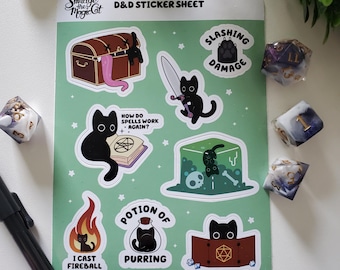 May include: A green D&D sticker sheet with black cat illustrations and phrases such as "Slashing Damage" and "Potion of Purring." The sheet includes a treasure chest, a sword, and a fireball design. Dice are scattered around the sheet.