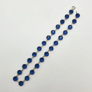 May include: Two strands of vintage jewelry featuring faceted, deep blue gemstones. The stones are evenly spaced and connected by a silver-toned metal. The jewelry is displayed against a white background.
