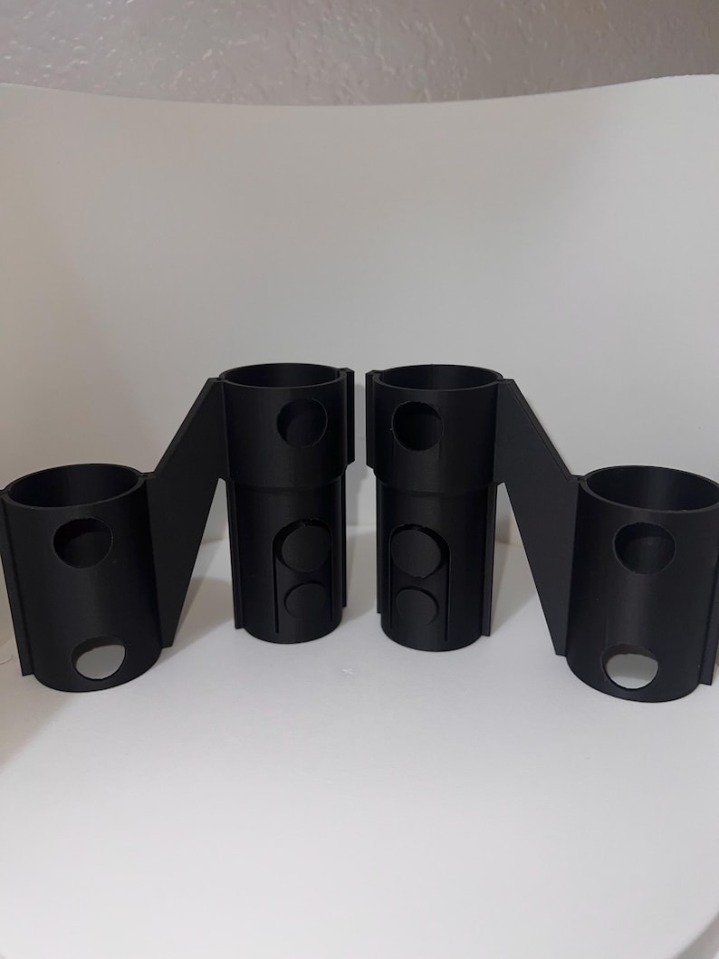 K&ouml;nnte beinhalten: Zwei schwarze, 3D-gedruckte Kunststoffteile mit mehreren L&ouml;chern. Die Teile sind so konzipiert, dass sie miteinander verbunden werden k&ouml;nnen.