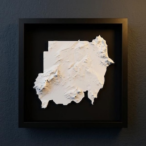 Könnte beinhalten: Eine gerahmte, dreidimensionale Reliefkarte des Sudan. Die Karte ist weiß und vor einem schwarzen Hintergrund in einem schwarzen quadratischen Rahmen angeordnet. Das Relief zeigt die Topographie des Landes mit detaillierten Graten und Tälern.