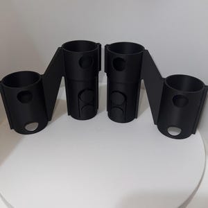 K&ouml;nnte beinhalten: Zwei schwarze 3D-gedruckte Kunststoffhalter mit mehreren L&ouml;chern. Die Halter sind so konzipiert, dass sie mehrere Gegenst&auml;nde aufnehmen k&ouml;nnen, wie z. B. Stifte, Bleistifte oder andere kleine Gegenst&auml;nde.