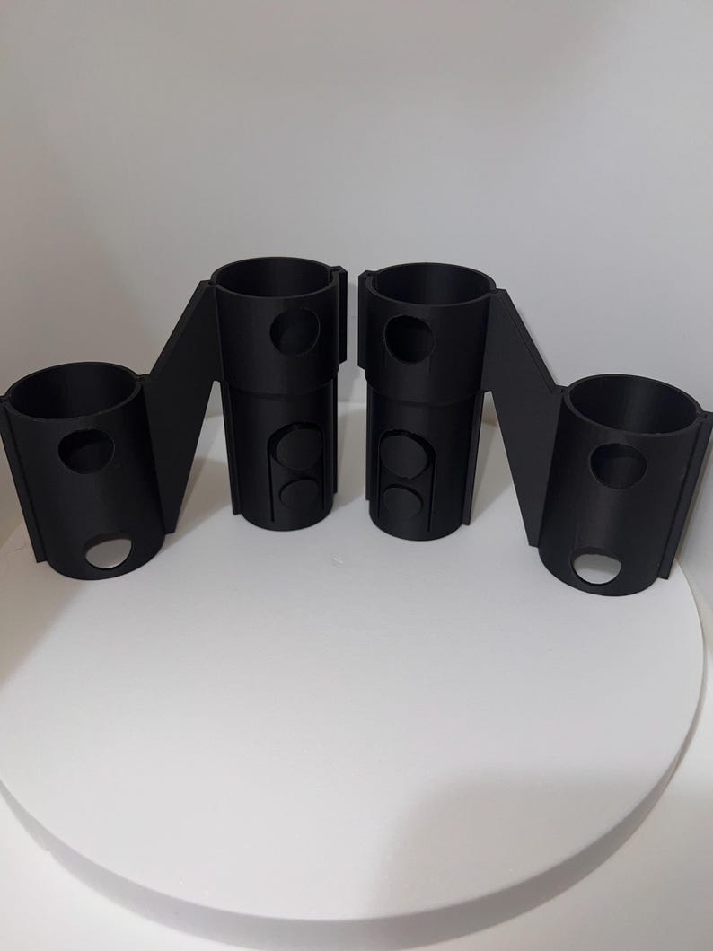 K&ouml;nnte beinhalten: Zwei schwarze 3D-gedruckte Kunststoffhalter mit mehreren L&ouml;chern. Die Halter sind so konzipiert, dass sie mehrere Gegenst&auml;nde aufnehmen k&ouml;nnen, wie z. B. Stifte, Bleistifte oder andere kleine Gegenst&auml;nde.