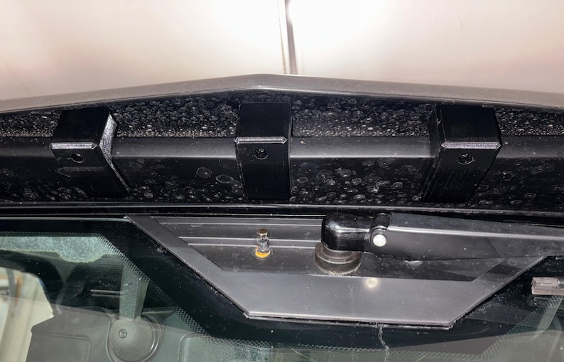 K&ouml;nnte beinhalten: Schwarzer Metall-Dachtr&auml;ger mit schwarzer Schaumstoffverkleidung und schwarzem Scheibenwischerarm. Der Dachtr&auml;ger ist an einem Fahrzeug montiert.
