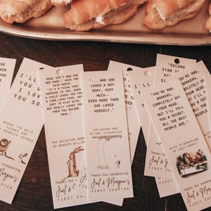 May include: A set of ten bookmark favors with illustrations from classic children's books. Each bookmark features a different book title and quote. The bookmarks are printed on a light pink background with brown text and illustrations.