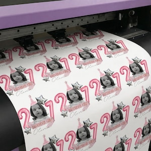 May include: A sheet of printed stickers featuring a young girl's photo, the number 2, and the text "Birthday Girl Olivia." The stickers have a pink and silver color scheme, with star and balloon accents. The stickers are printed on a white background.