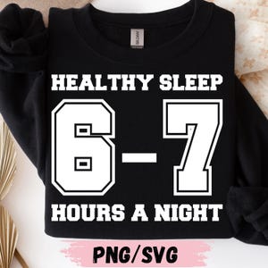 Op de afbeelding: Zwart sweatshirt met witte tekst. Er staat "HEALTHY SLEEP" boven de cijfers "6-7" in een vetgedrukte, omlijnde letter. Daaronder staat "HOURS A NIGHT". De onderkant heeft "PNG/SVG" in een roze rechthoek.