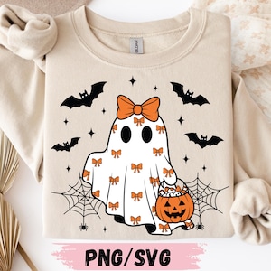 May include: A beige crewneck sweatshirt featuring a graphic of a white ghost wearing a large orange bow on its head. The ghost is covered in small orange bow patterns and holds an orange jack-o'-lantern bucket. Black bats, spiderwebs, and stars surround the ghost.