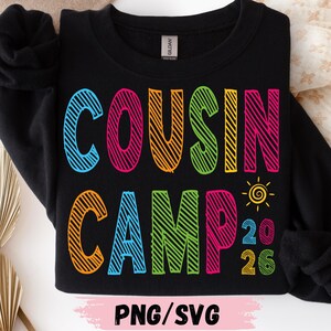 May include: Black sweatshirt featuring the text "COUSIN CAMP" in vibrant, block letters. The year "2026" is displayed below, with a small sun graphic. The bottom of the image has the text "PNG/SVG".