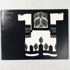 May include: A black and white postcard featuring a stylized illustration of a garment. The garment design is white with intricate black patterns and details. The text "Cut My Cote" is at the top left.