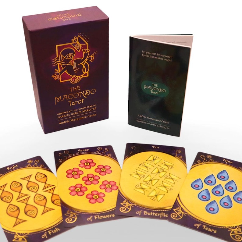 Op de afbeelding: Een paarse doos met gouden letters die "The Macondo Tarot" lezen, ge&iuml;nspireerd door de personages van Gabriel Garcia Marquez. De doos bevat een deck tarotkaarten met illustraties van vissen, bloemen, vlinders en tranen.