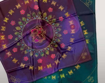 Op de afbeelding: Twee vierkante zijden sjaals met een mandala-ontwerp. De bovenste sjaal is paars met gouden en roze accenten en heeft een gestileerd figuur in het midden. De onderste sjaal is teal met gouden accenten.