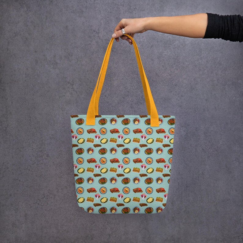 Pu&ograve; includere: Una borsa tote blu chiaro con manici gialli e un motivo di illustrazioni di cibo colorate. La borsa &egrave; realizzata in tela e ha un interno spazioso.