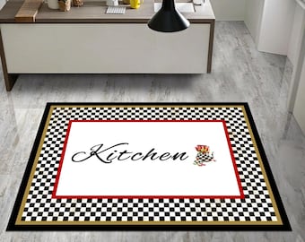 Może przedstawiać: Prostokątny dywan kuchenny z czarno-białą szachownicą. Dywan ma czerwoną obwódkę wokół białego środka ze słowem "Kitchen" w kursywie. Mała grafika czapki kucharskiej i kwiatów znajduje się w rogu.