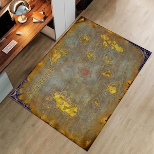 Puede incluir: Una alfombra rectangular con un mapa de Azeroth, con masas terrestres amarillas y marrones sobre un fondo azul grisáceo. La alfombra tiene un borde decorativo y la palabra "Azeroth" está impresa.