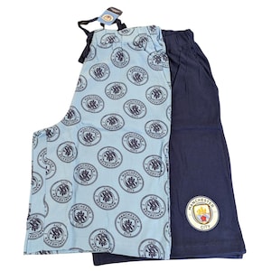 Op de afbeelding: Tweedelige pyjamaset. Een lichtblauwe pyjamabroek met een herhalend patroon van een teamlogo. De andere is marineblauw met een teamlogo op de broekspijp. Een label is bevestigd.