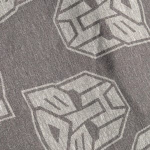 May include: Close-up of a gray fabric with a repeating pattern of a stylized, geometric emblem in a lighter gray. The emblem has a hexagonal shape with angular lines and shapes, creating a textured appearance.