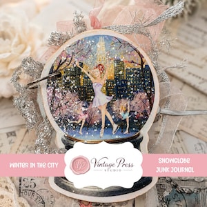 May include: A circular snow globe ornament featuring a city skyline with three figures ice skating. The design includes silver glitter accents, a dark base, and decorative pink and silver ribbons attached to a metal ring for hanging.