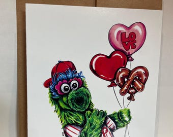 Single greeting card of Philadelphia’s favorite baseball mascot Phillies Phanatic holding love balloons and a Philly pretzel balloon