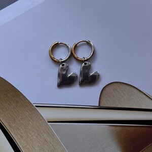 Mixed metal earrings with chrome heart pendant and stainless steel huggie hoops. Two tone gold and silver heart hoop earrings, minimalist lightweight jewelry for everyday wear. Small stainless steel hoops with polished heart charm, hypoallergenic and tarnish resistant. Modern mixed metal earrings perfect for stacking, casual outfits, and gift for her. Two tone huggie hoop earrings with chrome heart pendant, jewelry organizer, small jewelry box, lymare jewels