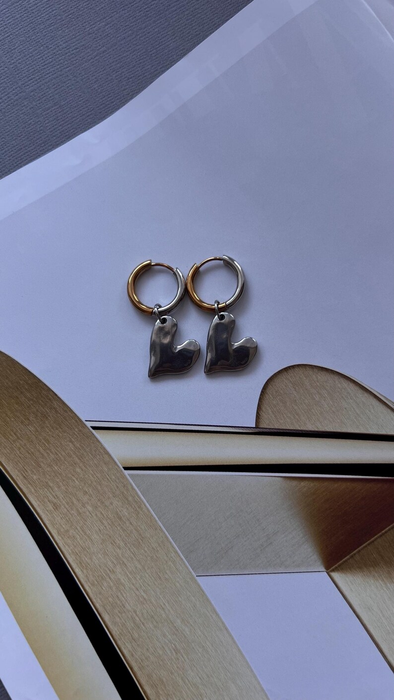 Mixed metal earrings with chrome heart pendant and stainless steel huggie hoops. Two tone gold and silver heart hoop earrings, minimalist lightweight jewelry for everyday wear. Small stainless steel hoops with polished heart charm, hypoallergenic and tarnish resistant. Modern mixed metal earrings perfect for stacking, casual outfits, and gift for her. Two tone huggie hoop earrings with chrome heart pendant, jewelry organizer, small jewelry box, lymare jewels