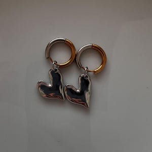 Mixed metal earrings with chrome heart pendant and stainless steel huggie hoops. Two tone gold and silver heart hoop earrings, minimalist lightweight jewelry for everyday wear. Small stainless steel hoops with polished heart charm, hypoallergenic and tarnish resistant. Modern mixed metal earrings perfect for stacking, casual outfits, and gift for her. Two tone huggie hoop earrings with chrome heart pendant, jewelry organizer, small jewelry box, lymare jewels
