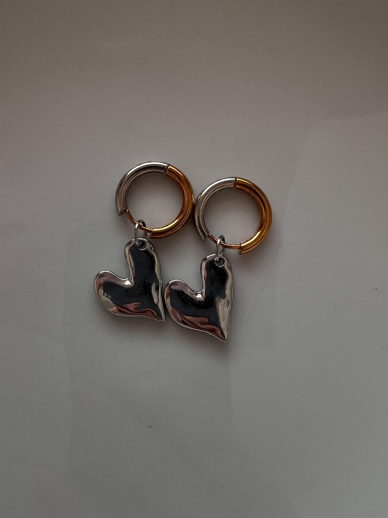 Mixed metal earrings with chrome heart pendant and stainless steel huggie hoops. Two tone gold and silver heart hoop earrings, minimalist lightweight jewelry for everyday wear. Small stainless steel hoops with polished heart charm, hypoallergenic and tarnish resistant. Modern mixed metal earrings perfect for stacking, casual outfits, and gift for her. Two tone huggie hoop earrings with chrome heart pendant, jewelry organizer, small jewelry box, lymare jewels