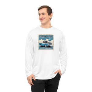Op de afbeelding: Wit shirt met lange mouwen met een retro grafische afbeelding van een blauwe Ford F150-truck en Route 66-bewegwijzering. De tekst "FORD F150" en "American Legends" worden ook weergegeven. Het shirt is gemaakt van een zacht, comfortabel materiaal.