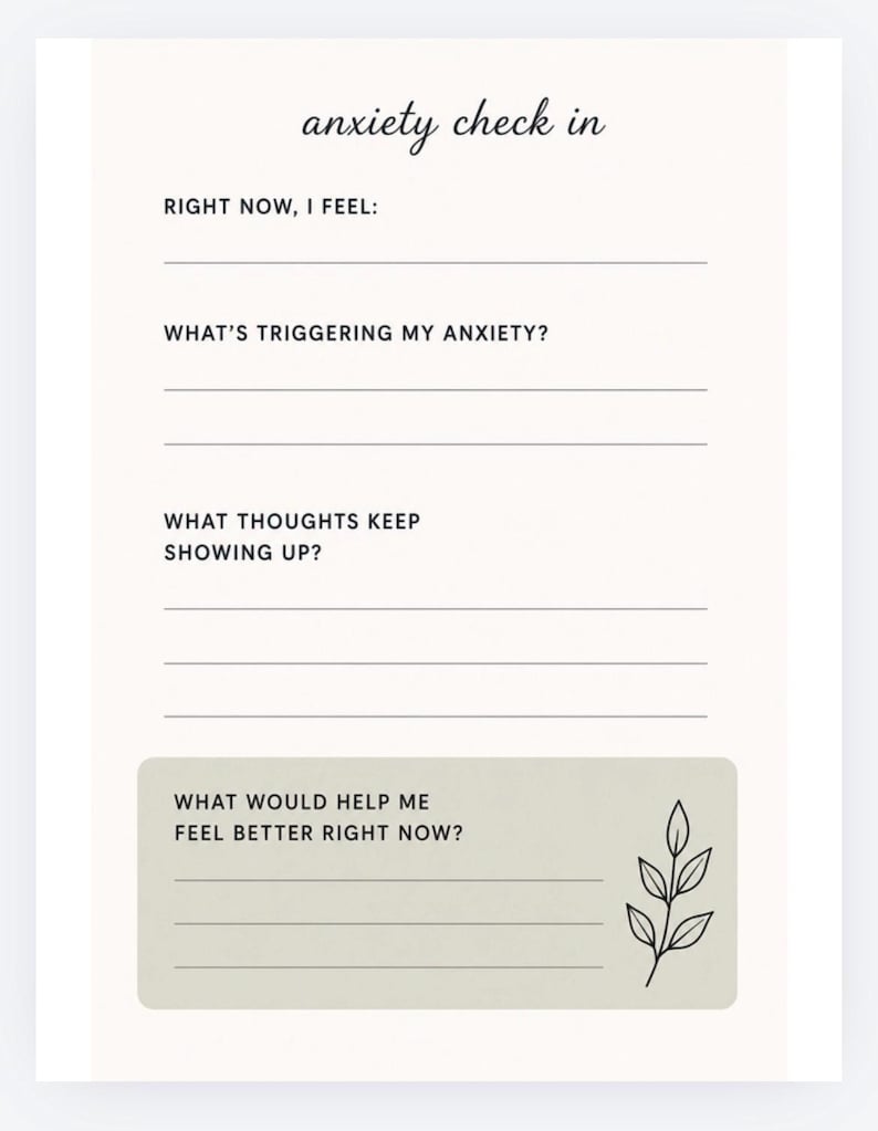 May include: A cream-colored journal page with the words "anxiety check in" in cursive. The page includes prompts such as "Right now, I feel:" and "What's triggering my anxiety?" A decorative leaf sprig is in the bottom right corner.