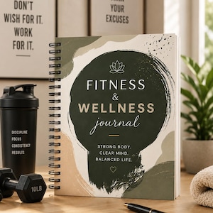 May include: A spiral-bound fitness and wellness journal with the text "FITNESS & WELLNESS journal" on the cover. The cover has a dark green circular design with a lotus flower icon. A black dumbbell weighing 10 lbs, a black shaker bottle, and a pen are also visible.