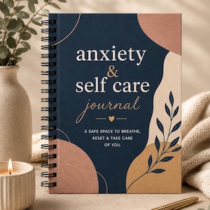 Może przedstawiać: Spiralny notatnik z napisem "anxiety & self care journal" na okładce. Okładka jest granatowa z abstrakcyjnymi kształtami w kolorze beżowym i brzoskwiniowym. Tekst "Bezpieczna przestrzeń do oddychania, resetowania i dbania o siebie" również na okładce.