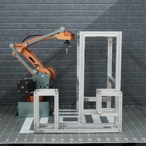 以下が含まれることがあります： 銅と灰色のカラーリングのロボットアームが、金属製のフレーム構造の前に配置されています。アームは伸ばされ、動いているように見えます。フレームは銀色のアルミニウム製で、長方形の形をしています。