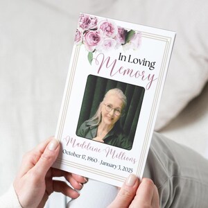 May include: A white memorial booklet with a floral design in pink and green. The booklet has a photo of a woman with gray hair and glasses. The text on the booklet reads "In Loving Memory, Madeline Millions, October 17, 1960 - January 3, 2025."