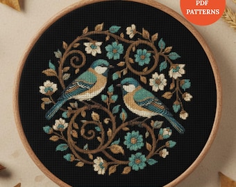 May include: Cross-stitch pattern featuring two blue and tan birds perched amidst teal and white flowers and brown vines, set against a black background. The design is framed in a wooden embroidery hoop. Text reads "INSTANT PDF PATTERNS" and "BUY 1 GET 3 FREE BONUS PATTERNS".