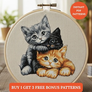 Op de afbeelding: Kruissteekborduurwerk van drie kittens in een houten hoepel. De kittens zijn grijs, zwart en oranje. De tekst "INSTANT PDF PATTERNS" staat in een rode cirkel. De tekst "BUY 1 GET 3 FREE BONUS PATTERNS" staat in een rood rechthoek.