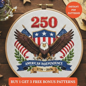 Puede incluir: Un patrón de punto de cruz en un aro de madera que presenta un águila con las alas extendidas, banderas americanas y el texto "250" en rojo. El diseño incluye las palabras "American Independence" y los años "1776-2026".